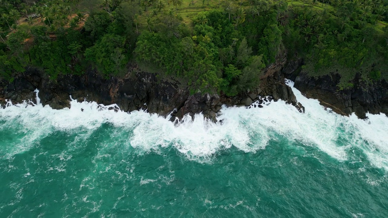 海滩鸟瞰图椰子树和巨大的海浪造成的强风造成的巨浪冲刷在泰国普吉岛海岸线上的山丘。视频素材