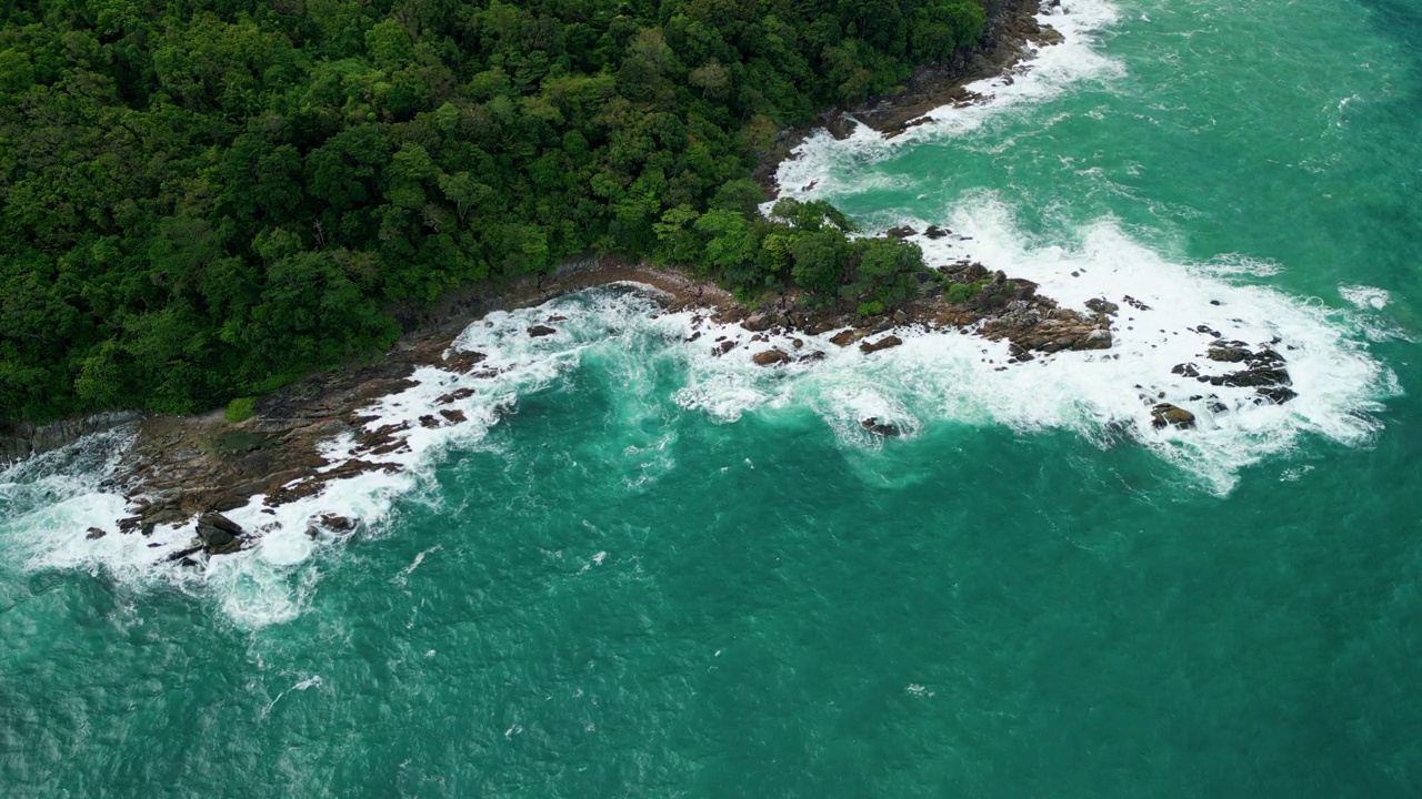 海滩鸟瞰图椰子树和巨大的海浪造成的强风造成的巨浪冲刷在泰国普吉岛海岸线上的山丘。视频素材