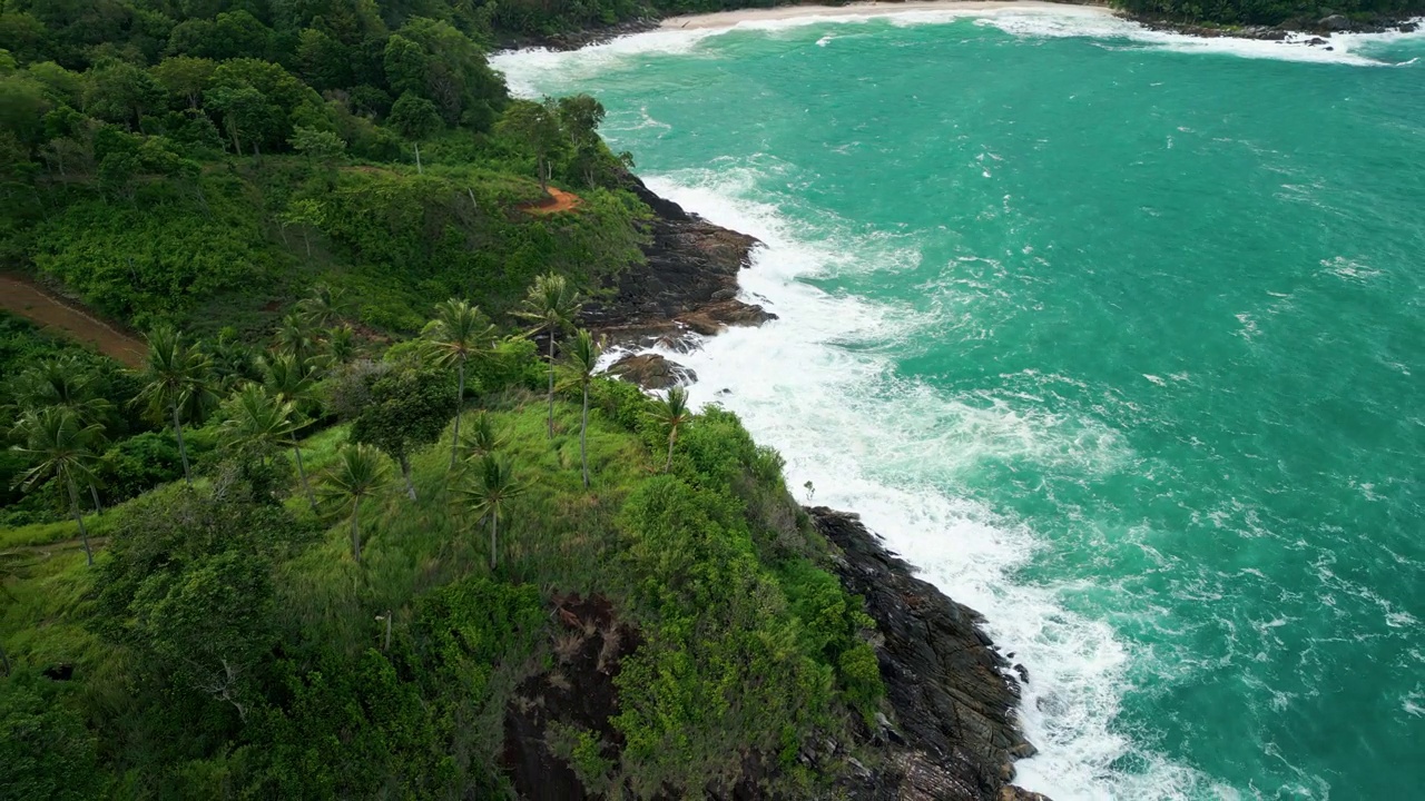 海滩鸟瞰图椰子树和巨大的海浪造成的强风造成的巨浪冲刷在泰国普吉岛海岸线上的山丘。视频素材