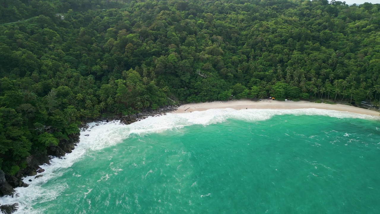 海滩鸟瞰图椰子树和巨大的海浪造成的强风造成的巨浪冲刷在泰国普吉岛海岸线上的山丘。视频素材