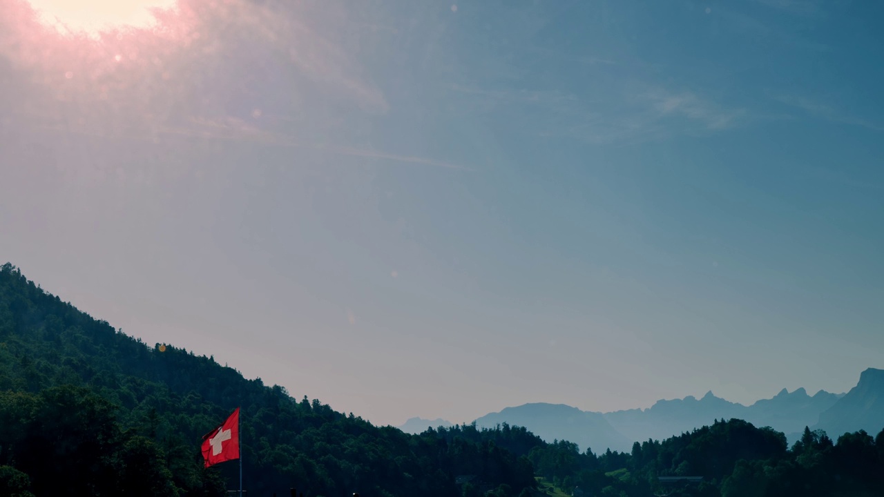 瑞士国旗在山上，在一个晴朗的夏日和天空视频素材