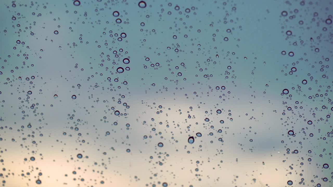 雨天，雨滴落在玻璃窗上，映衬着蓝天。视频素材