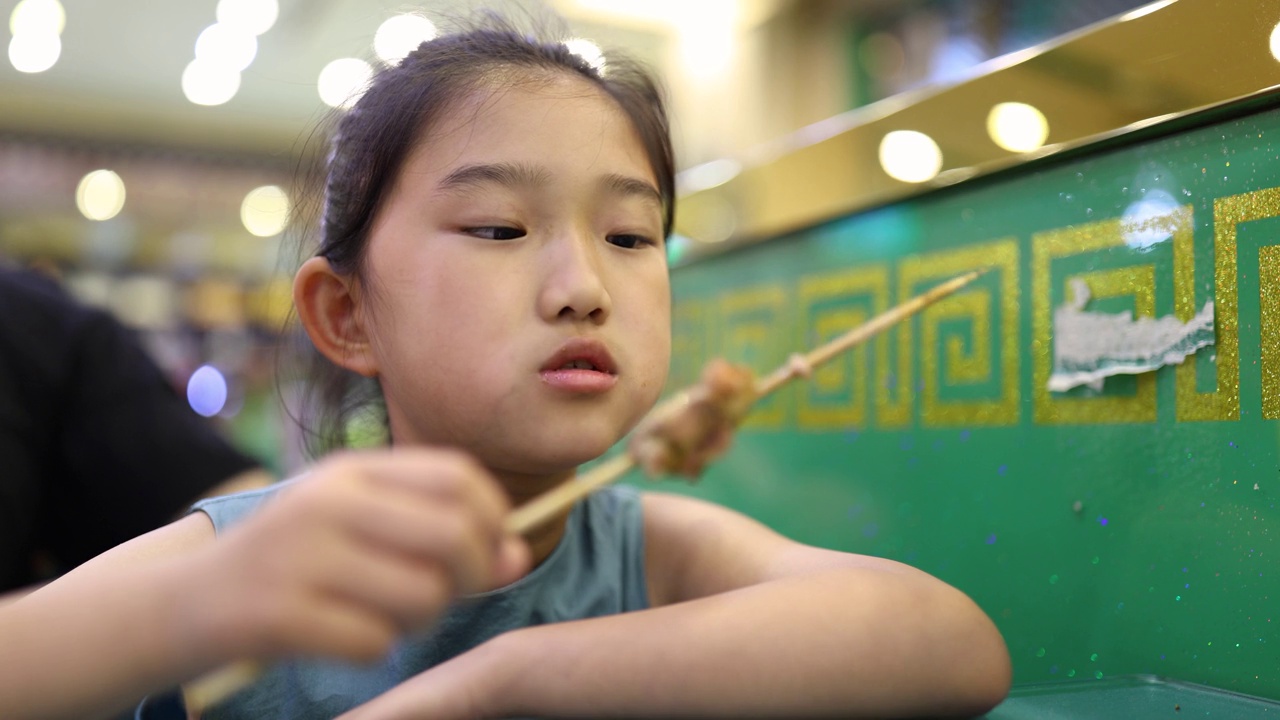 小女孩在吃羊肉串视频素材