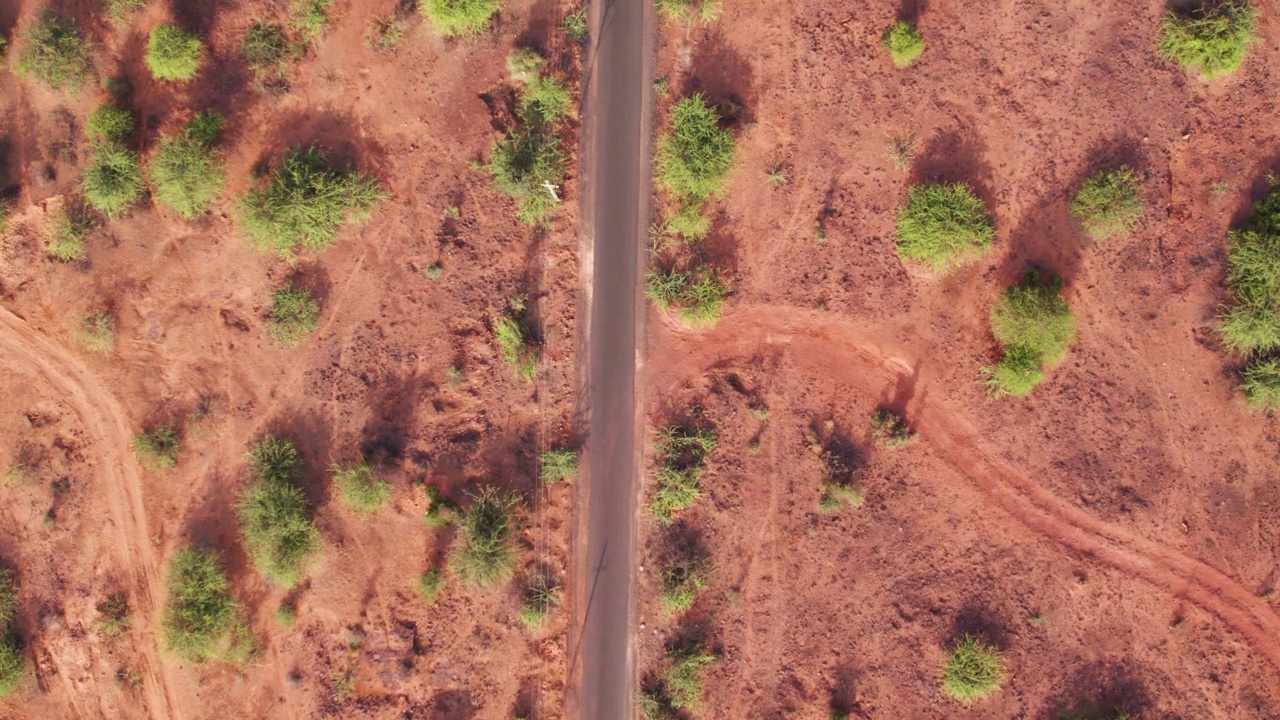 4K俯拍的印度古吉拉特邦库奇布吉附近沙漠地区空旷的道路，路边有灌木丛。道路俯视图。视频素材