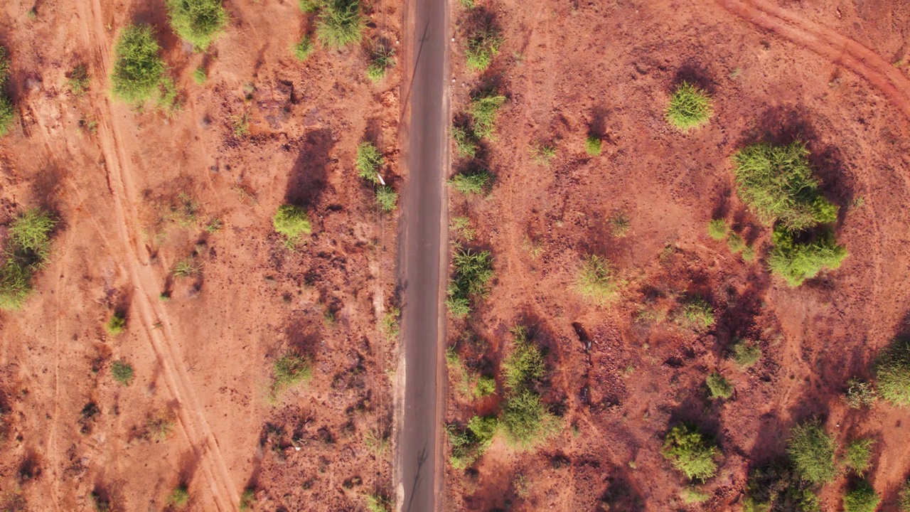 4K俯拍的印度古吉拉特邦库奇布吉附近沙漠地区空旷的道路，路边有灌木丛。道路俯视图。视频素材