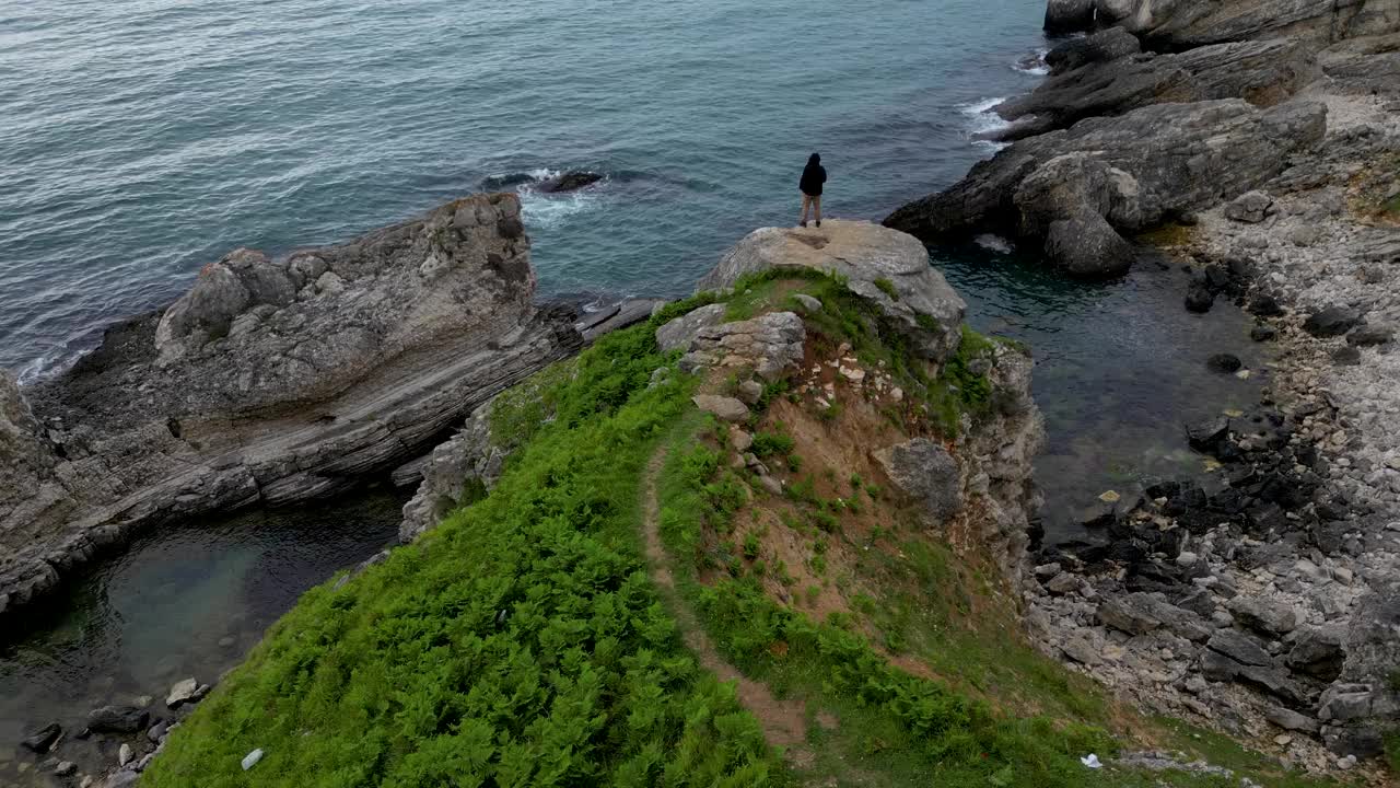 一个人站在悬崖边，看着平静的大海视频素材