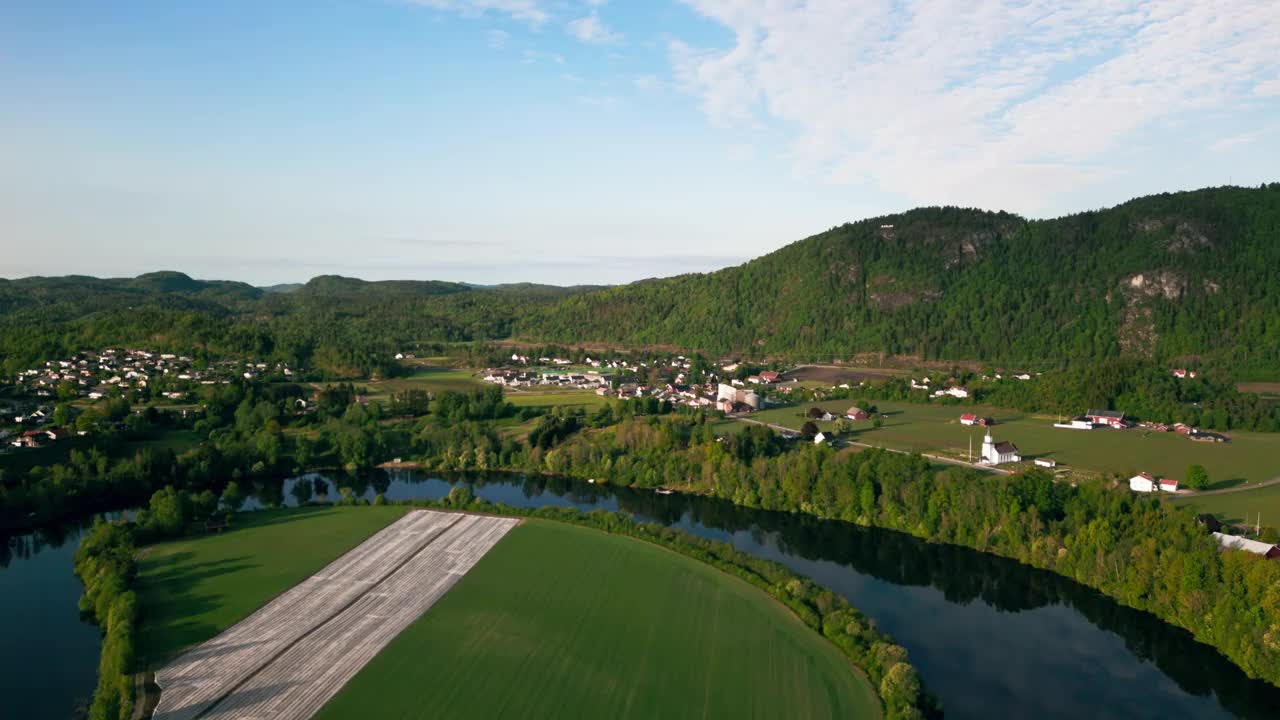鸟瞰图在挪威的绿色山丘的河边草坪上的乡村房屋视频素材