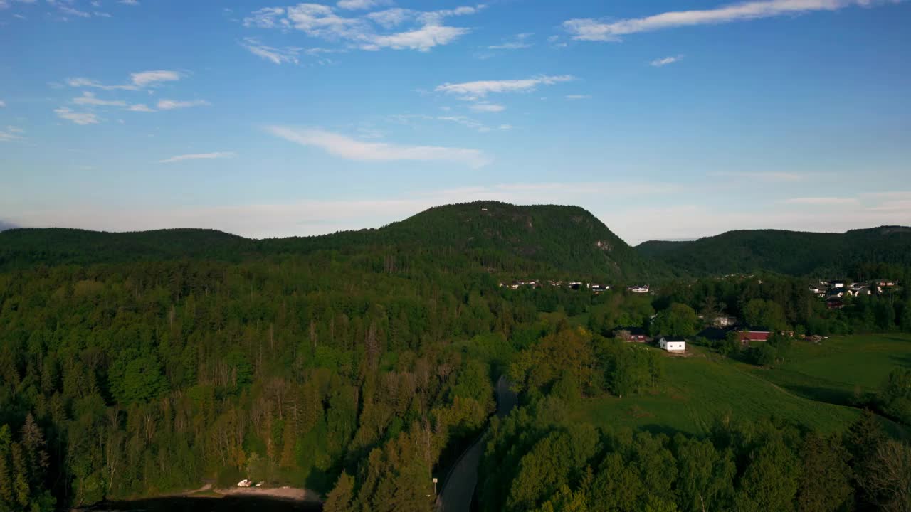 鸟瞰图，挪威的乡村房屋在河边的草坪上，有绿色的山丘视频素材