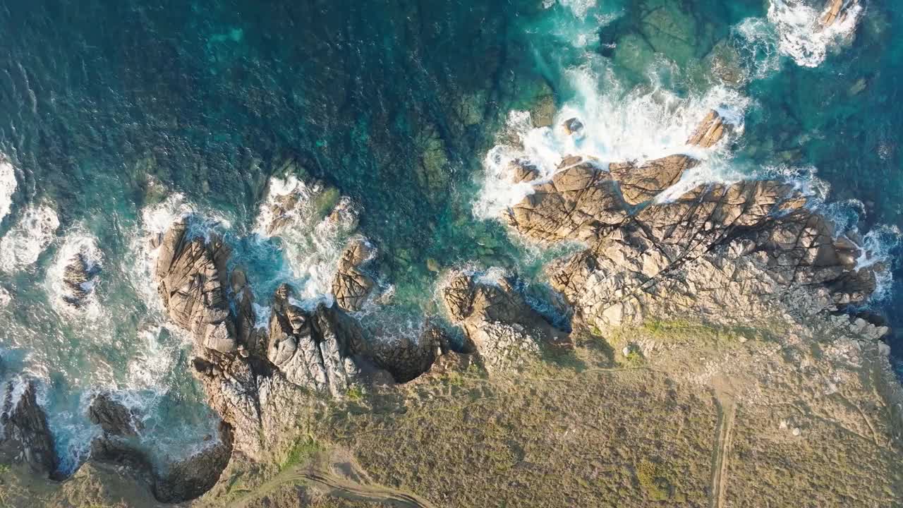 鸟瞰在岩石海岸飞溅的泡沫海浪视频素材