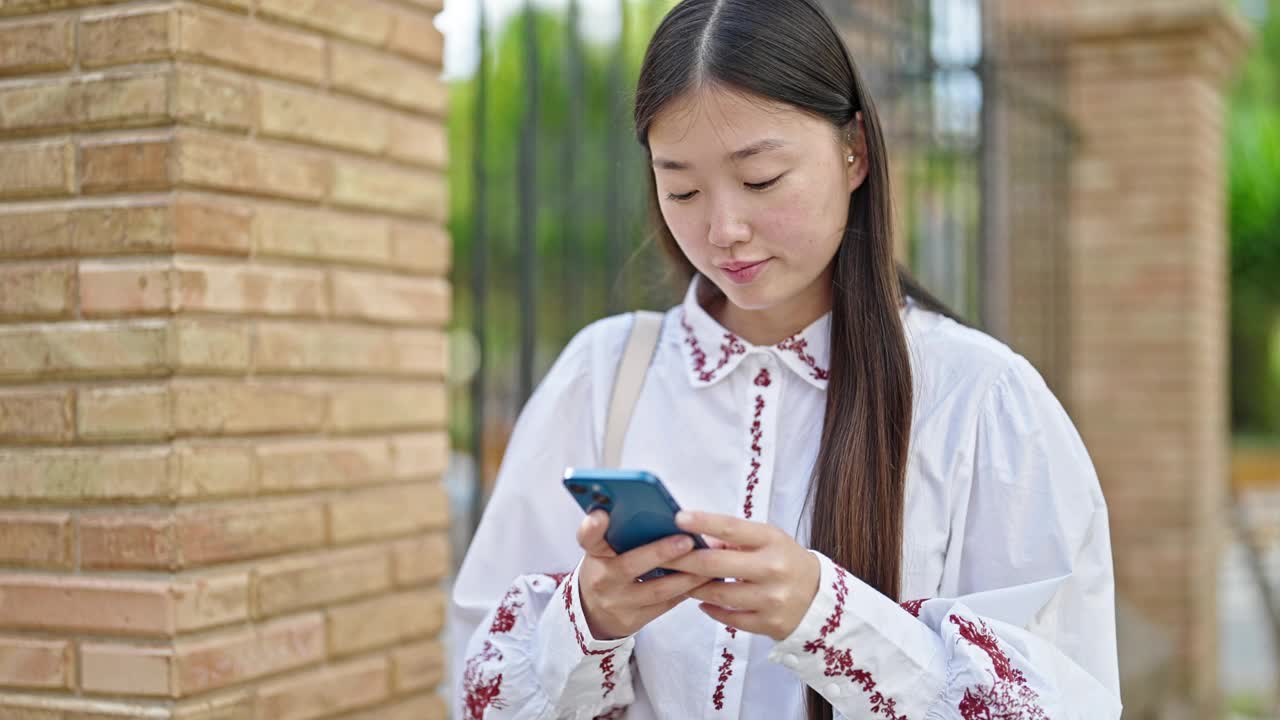 年轻的中国女子在街上边听音乐边用智能手机跳舞视频素材