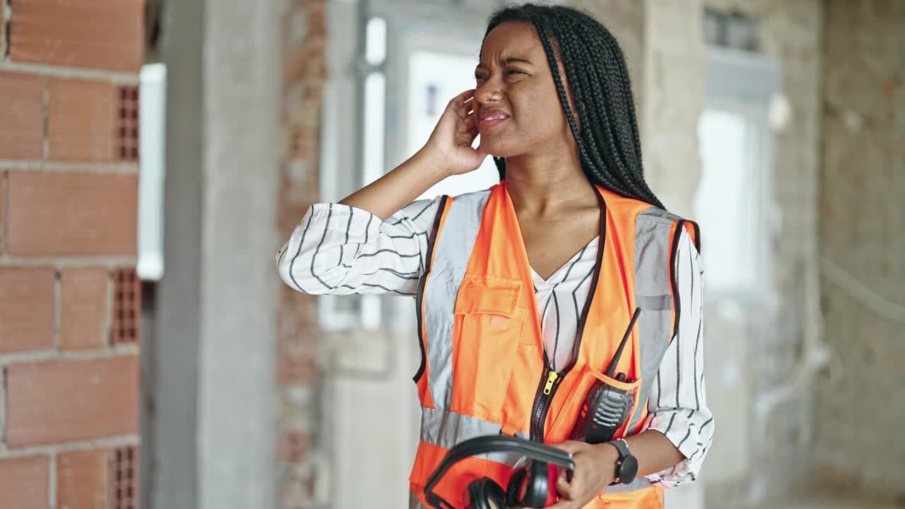 非裔美国女建筑工在工地戴着耳机听噪音视频素材