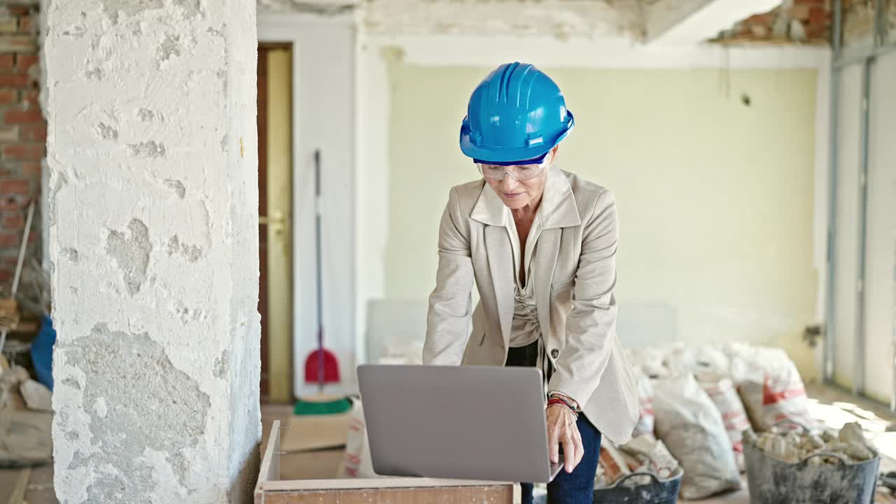 中年金发女建筑师在工地用笔记本电脑取下眼镜视频素材