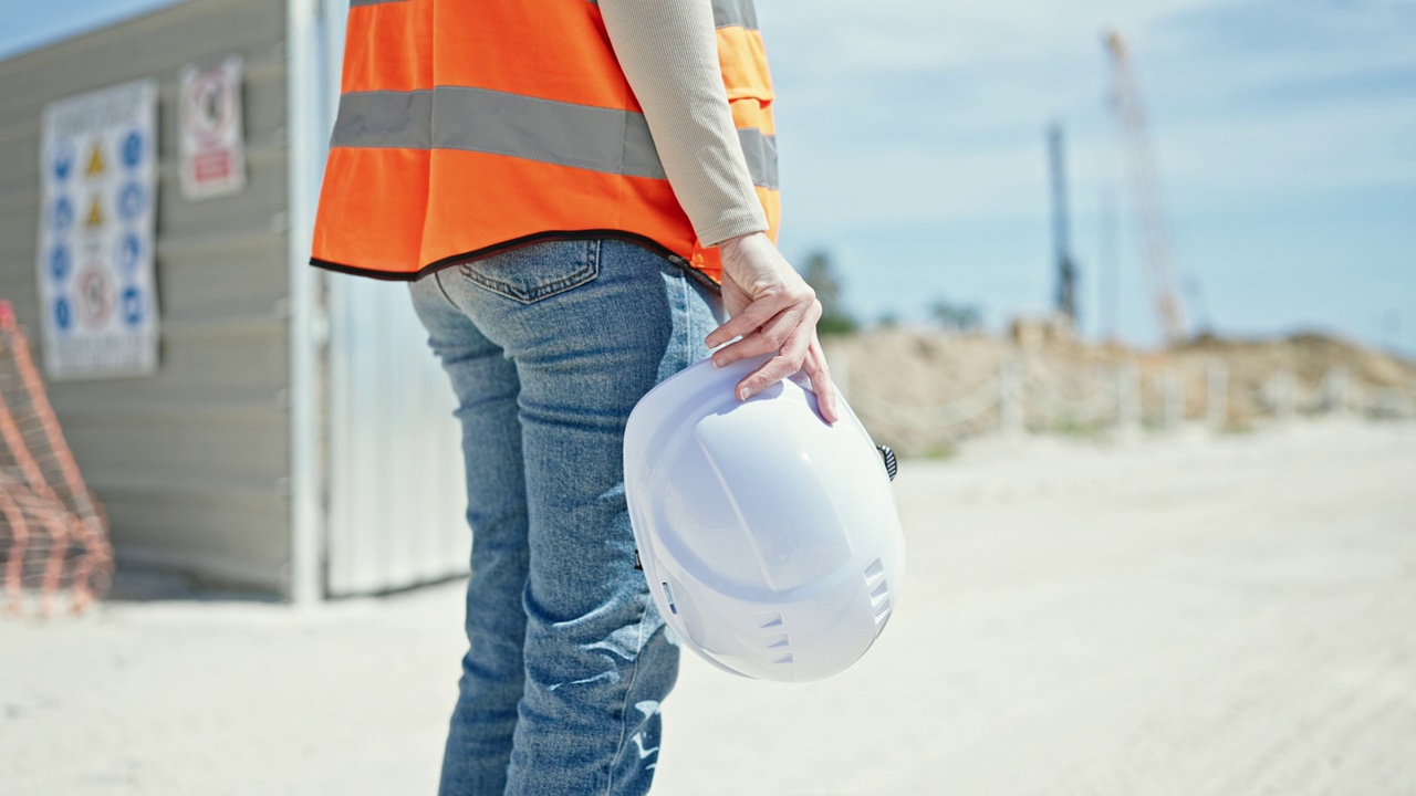 年轻漂亮的西班牙女建筑工人在街上举着安全帽视频素材