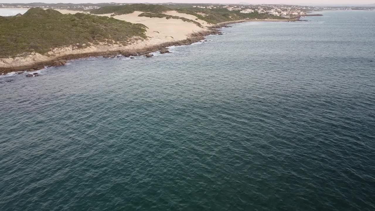 在夕阳的天空下，泡沫的大海冲击着岩石的海岸视频素材