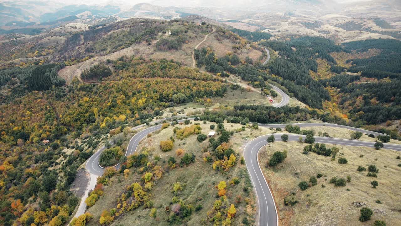 秋天夕阳下山谷里蜿蜒的小路。沥青山路鸟瞰图视频素材