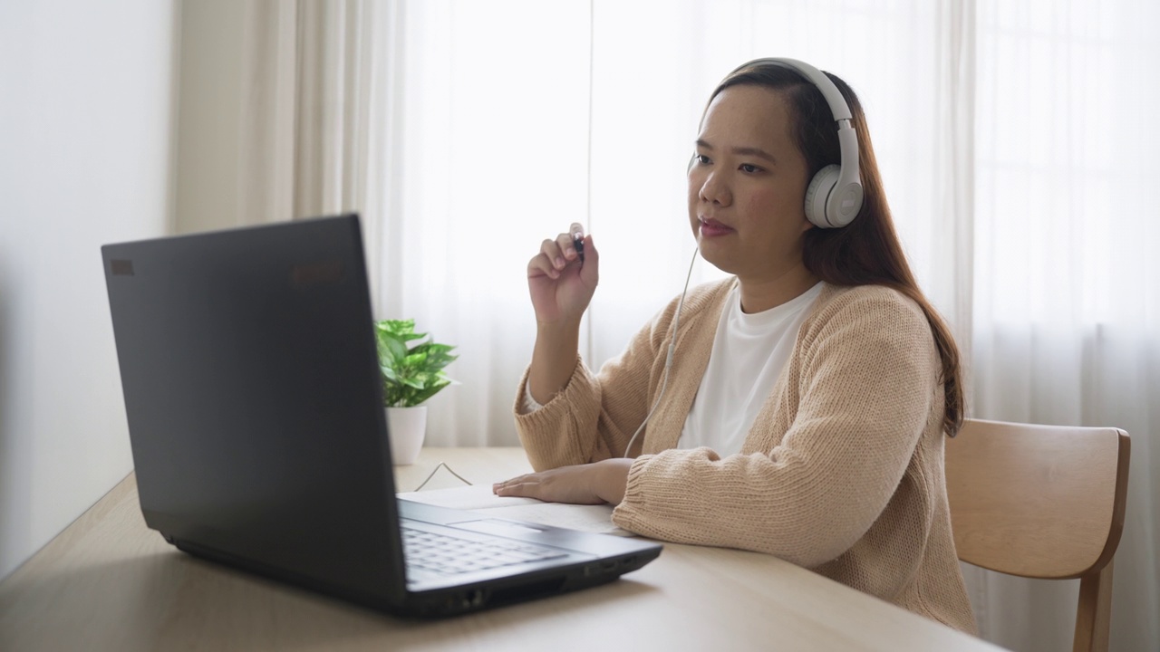 戴着耳机的女商人在家里通过视频会议开会视频素材