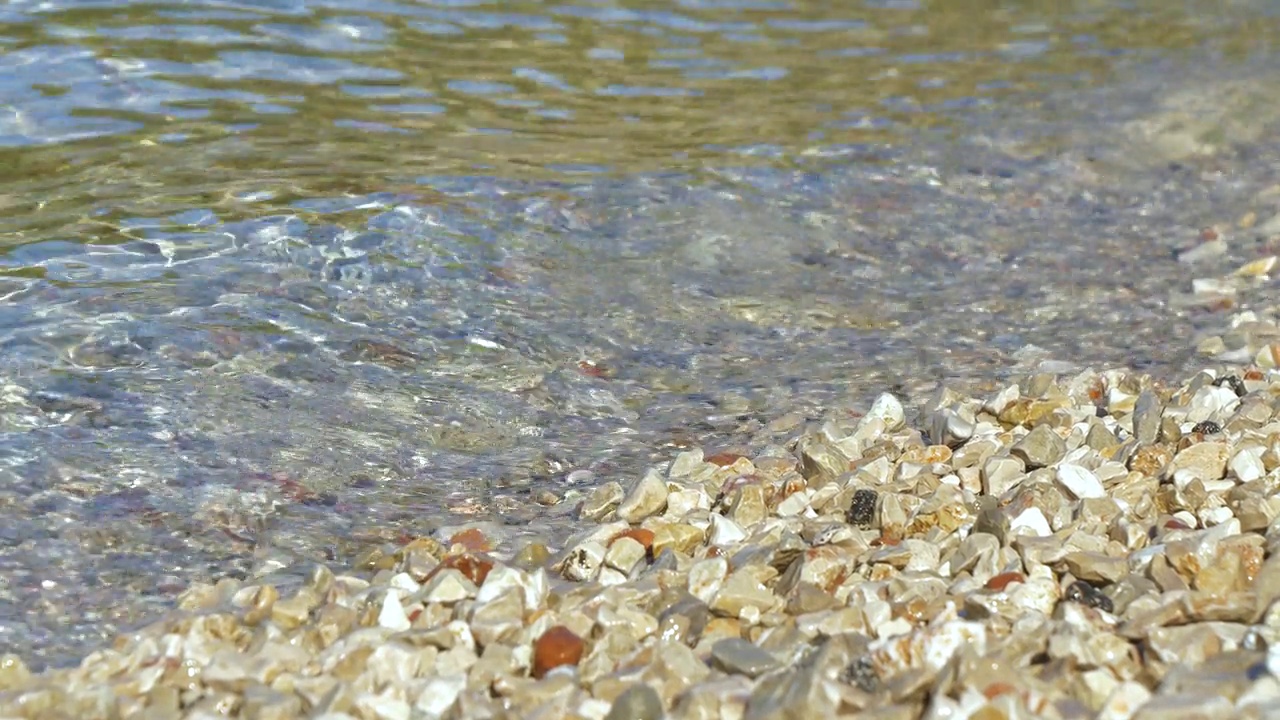 清澈的海浪拍打着亚得里亚海布满鹅卵石的海岸视频素材