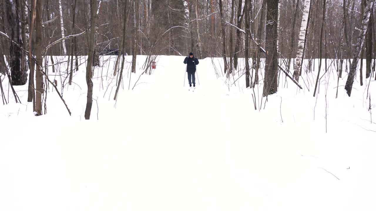 一个50岁的男人冬天在森林里滑雪视频素材