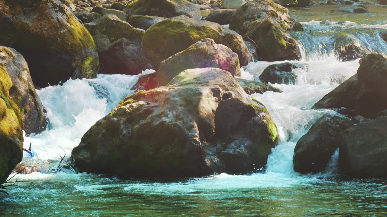 山河在阳光下流淌。水在自然公园的大岩石上流动视频素材