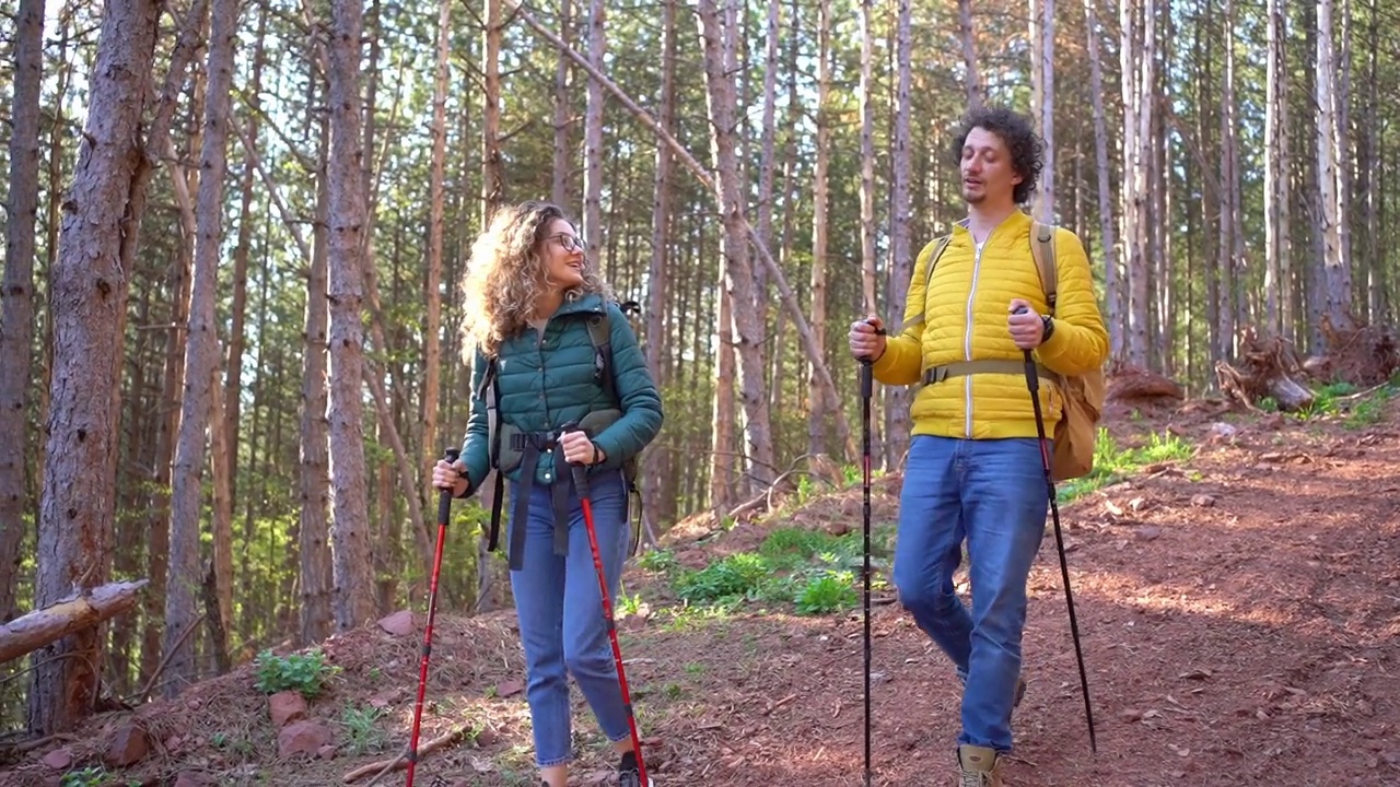 年轻的爱冒险的夫妇背着背包在森林里徒步旅行，他们在聊天视频素材