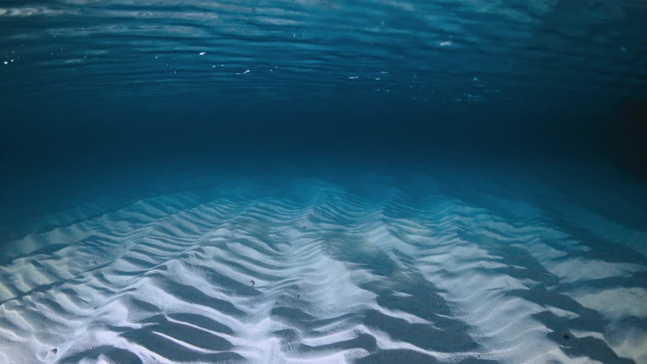 有波浪的透明海洋，有灯笼的夜晚水下的沙底视频素材