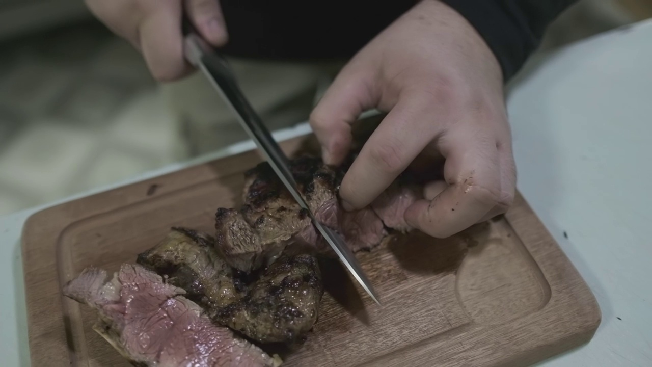 厨师用刀在菜板上切熟肉块视频素材