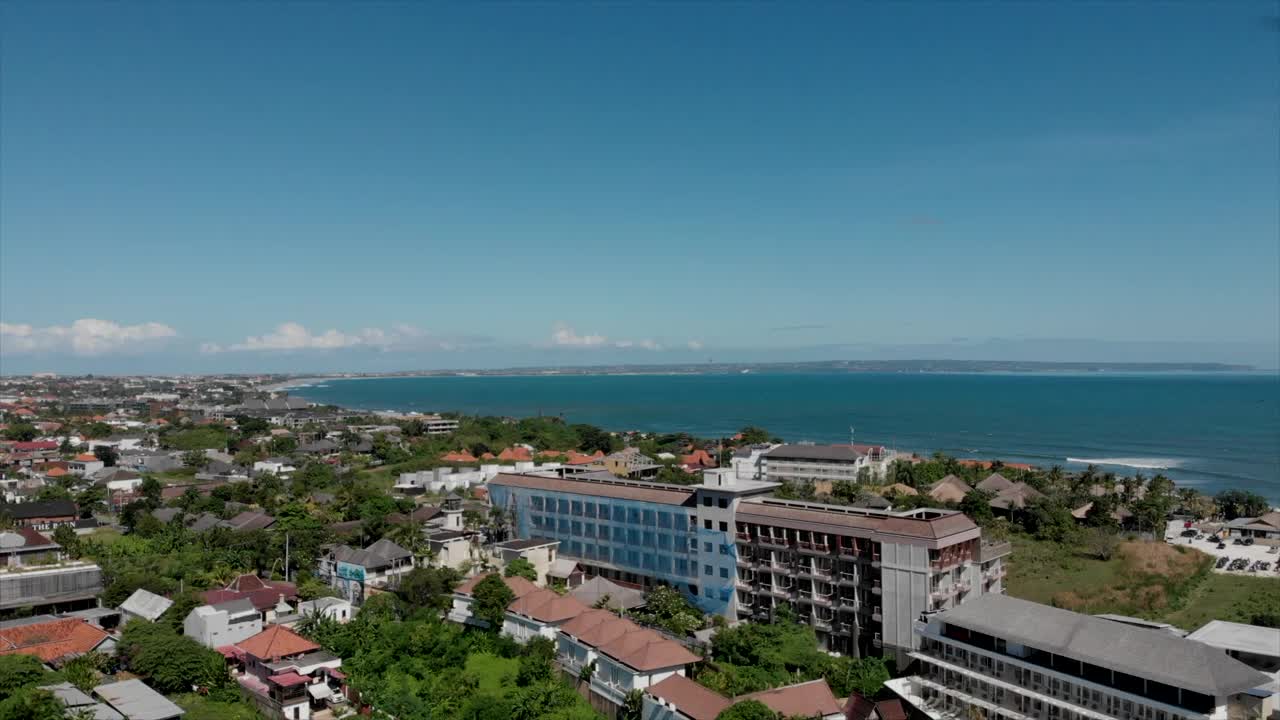 在阳光明媚的日子里，苍谷旅游区在海湾的鸟瞰图与当地的房屋和建筑酒店和绿色植物。巴厘岛,印度尼西亚。视频素材