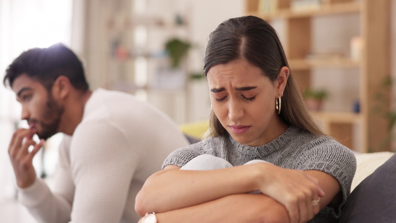 一对夫妇，悲伤的女人在客厅的沙发上争执或争吵后离婚，争执或不愉快的家庭关系。情绪化的女人和男人会因为分手、出轨或吵架而哭泣视频素材