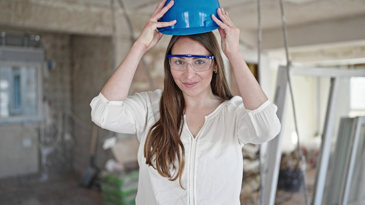 年轻美丽的西班牙女建筑工人微笑自信地戴着安全帽在建筑工地视频素材