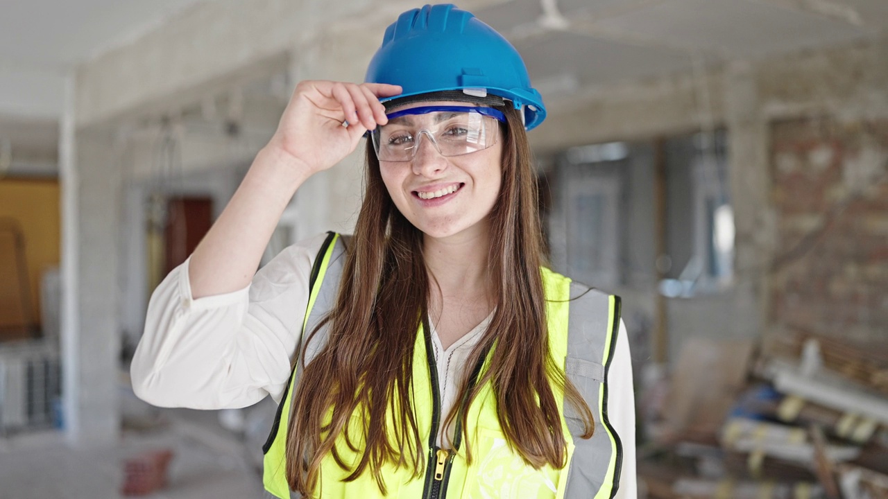 年轻美丽的西班牙女建筑工人微笑自信地站在建筑工地视频素材