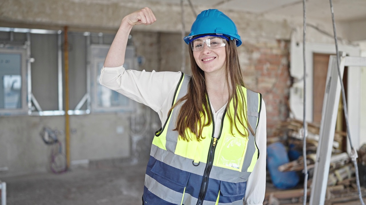 年轻美丽的西班牙女建筑工人微笑着自信地在建筑工地用手臂做了一个有力的手势视频素材