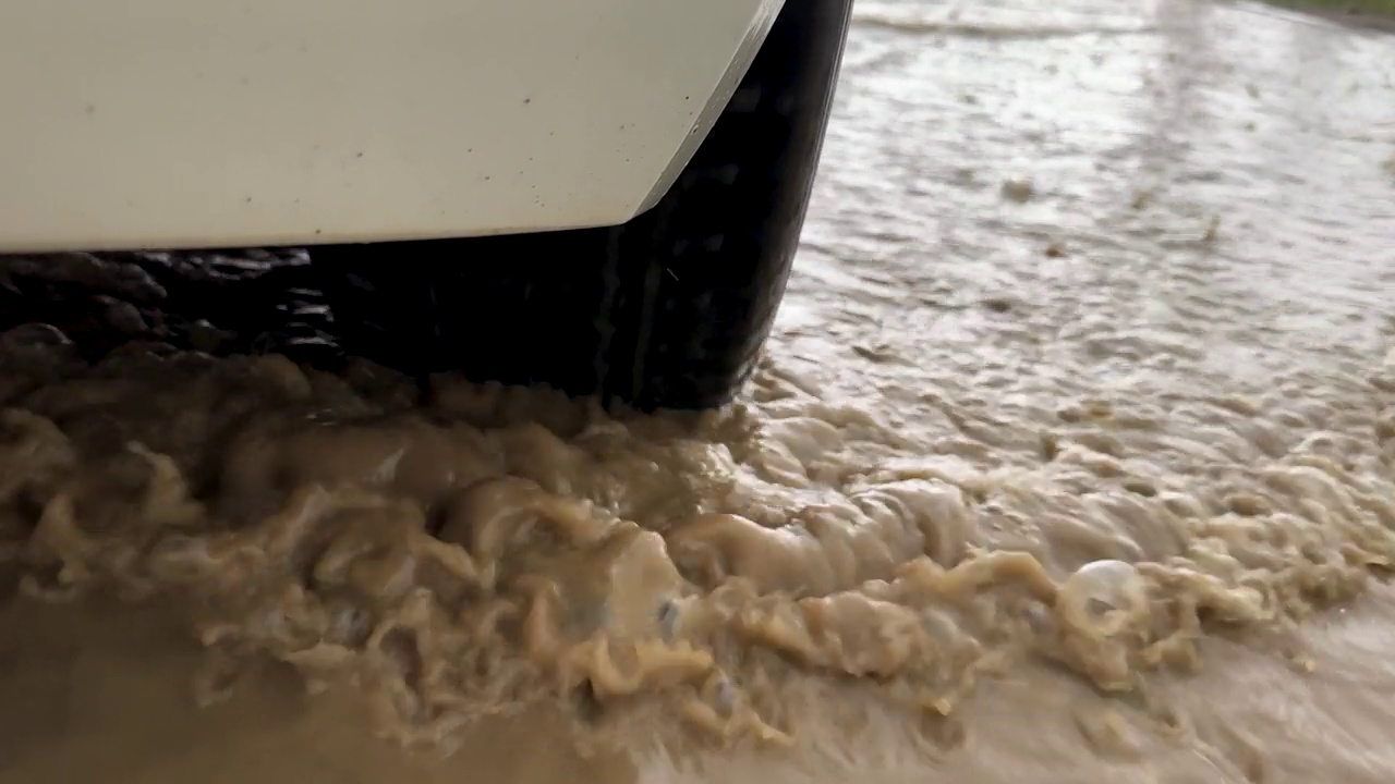 汽车在雨中驶过，轮胎把水溅到空中视频素材