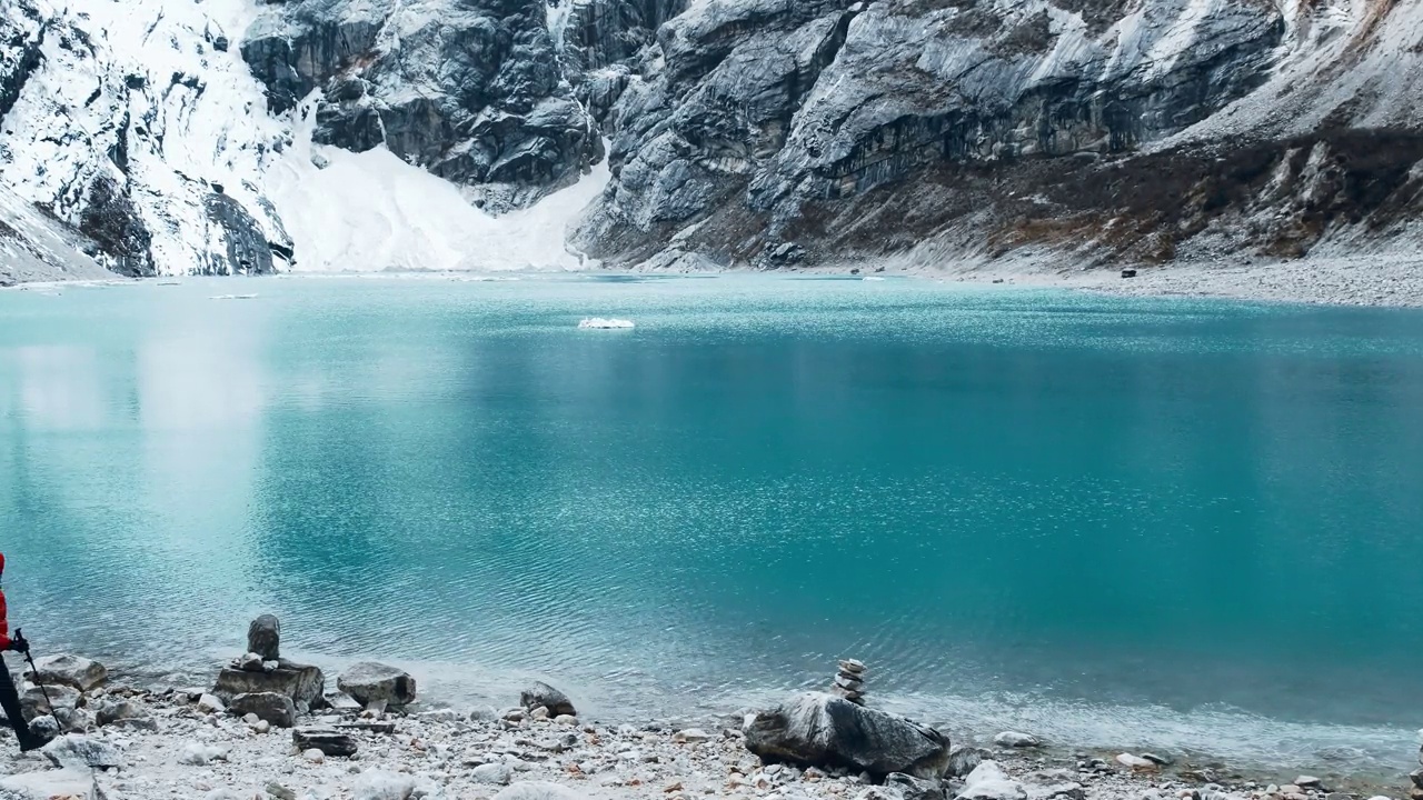 一个人站在山间湖泊前的悬崖边上视频素材