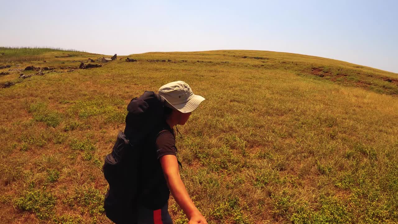 一名亚洲女性独自旅行者的慢动作自拍，在西玉屏屿澎湖北岸海岸的干燥的沙漠山坡上，向废弃的古玩历史遗址村走去视频素材