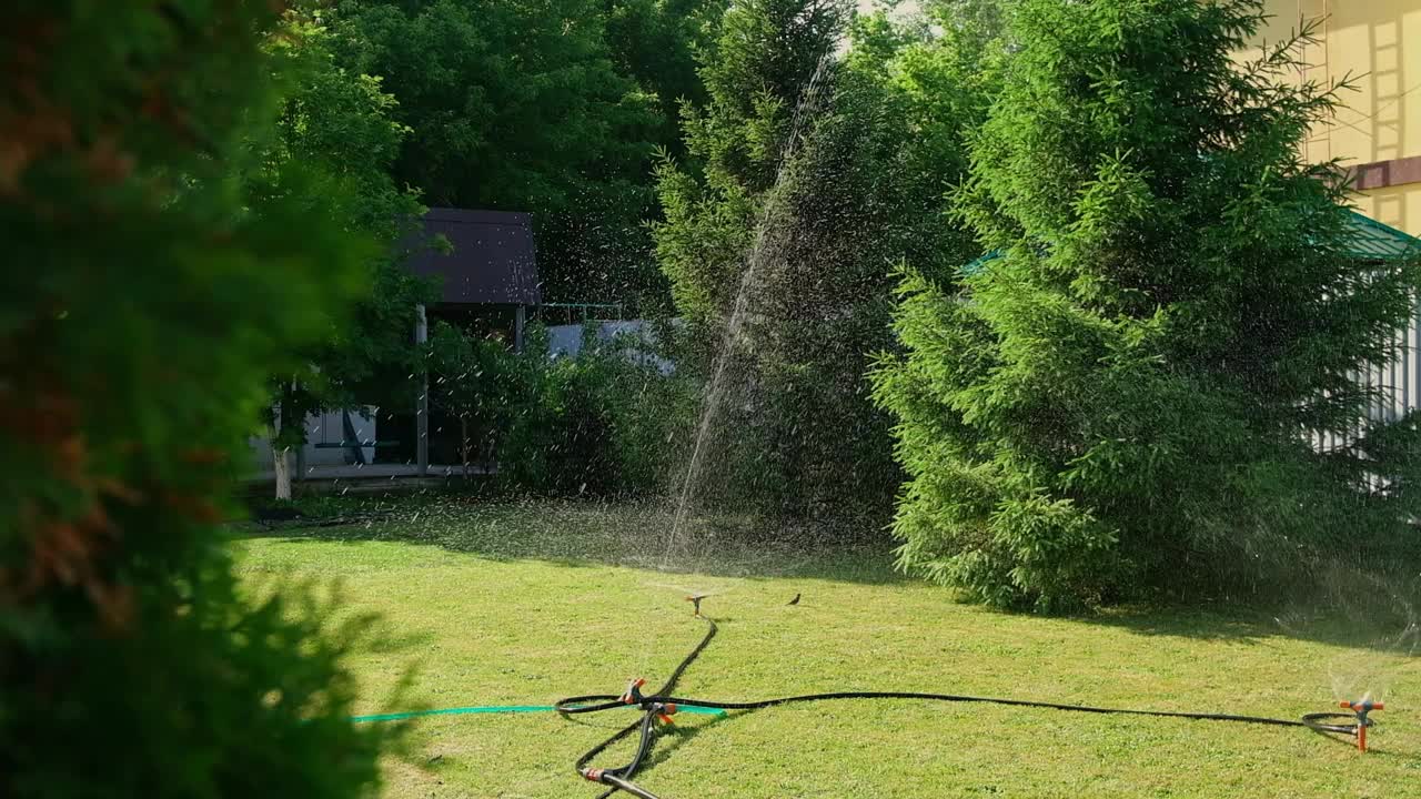 院子里的草坪用喷水器自动浇水。水花在草地上飞舞。户外慢动作镜头视频素材