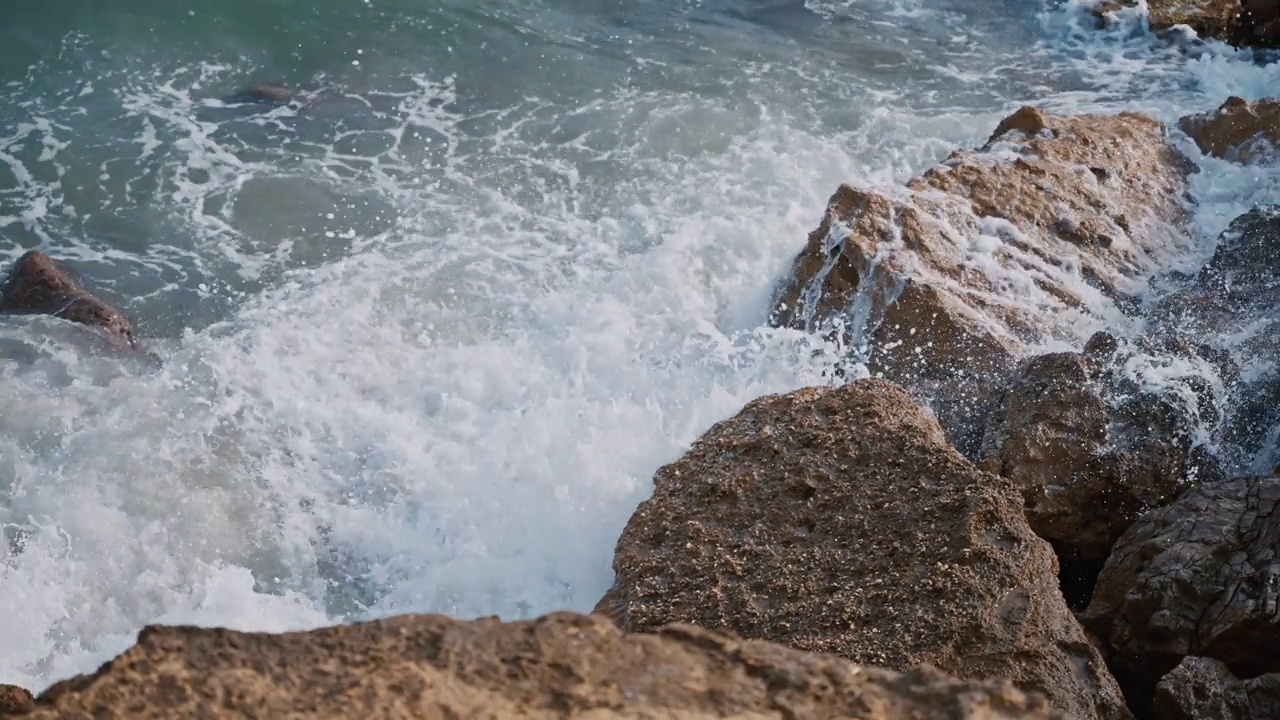 夏天阳光灿烂的日子里，海浪冲击着海滩上的岩石视频素材