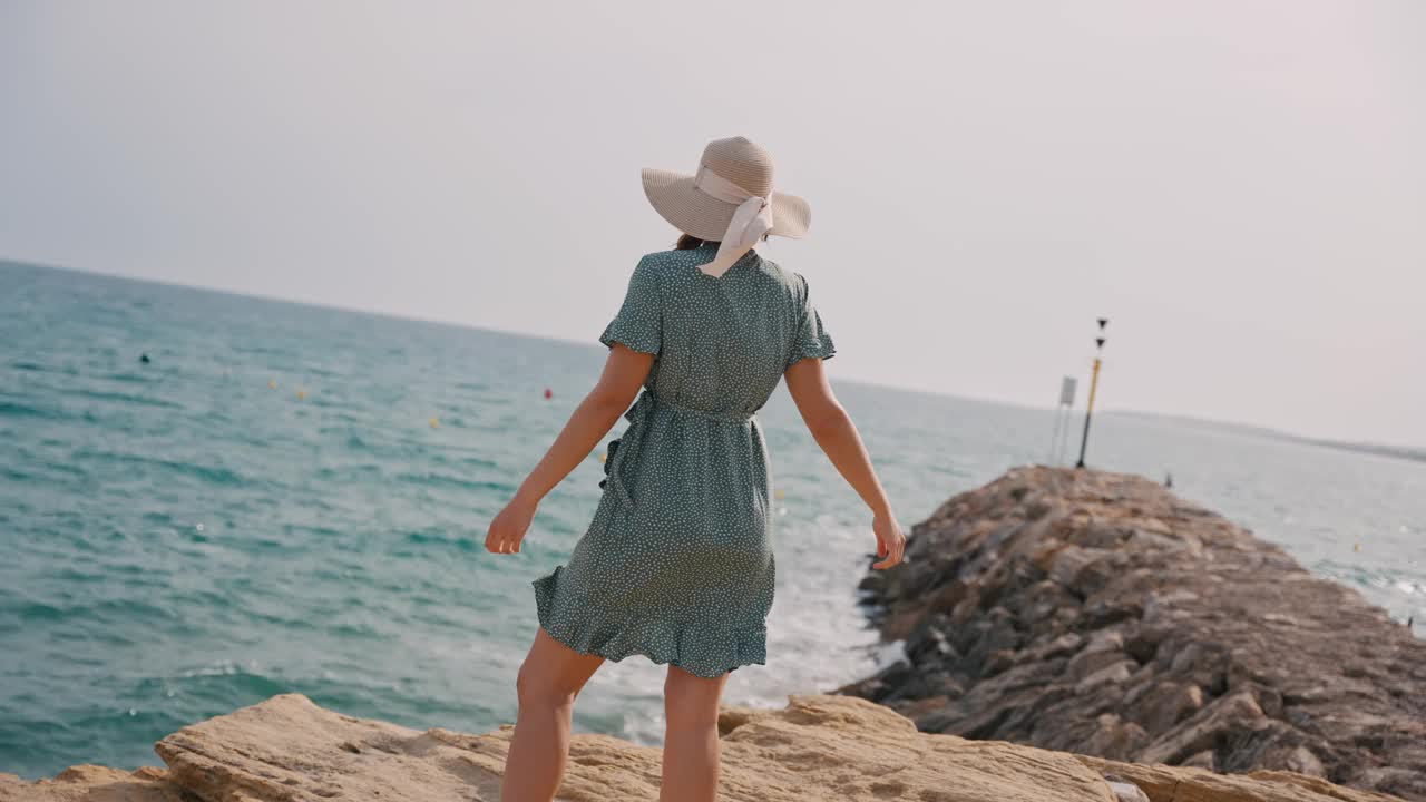 欢快的女人在岩石海岸上欢快地旋转，拥抱夏日的微风和完美假期的幸福海滩氛围视频素材