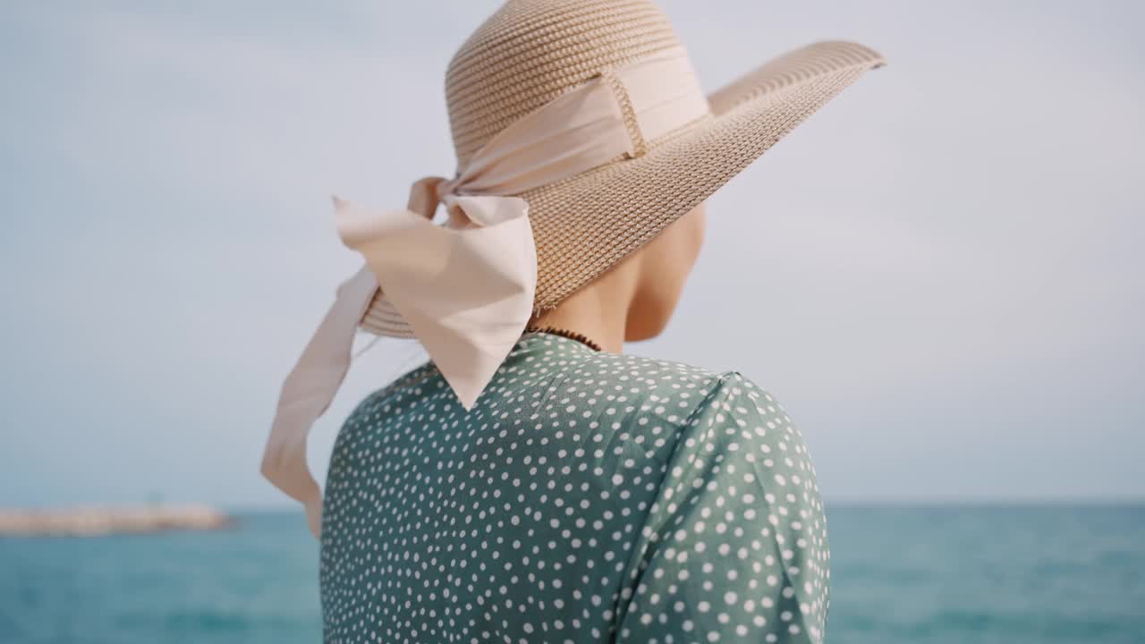 暑假戴着太阳帽在海滩享受海风的快乐年轻女子视频素材