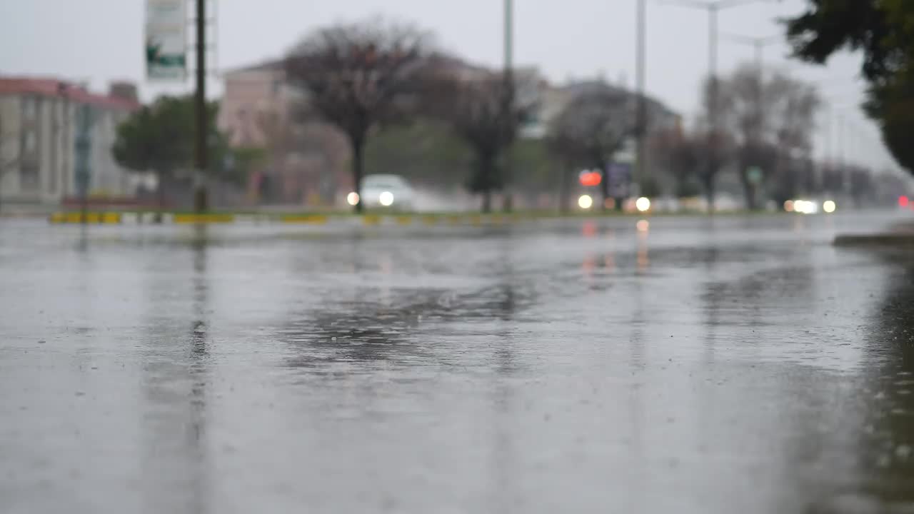 交通城市傍晚，雨点落在水坑上，灯光反射在城市人行道上视频下载