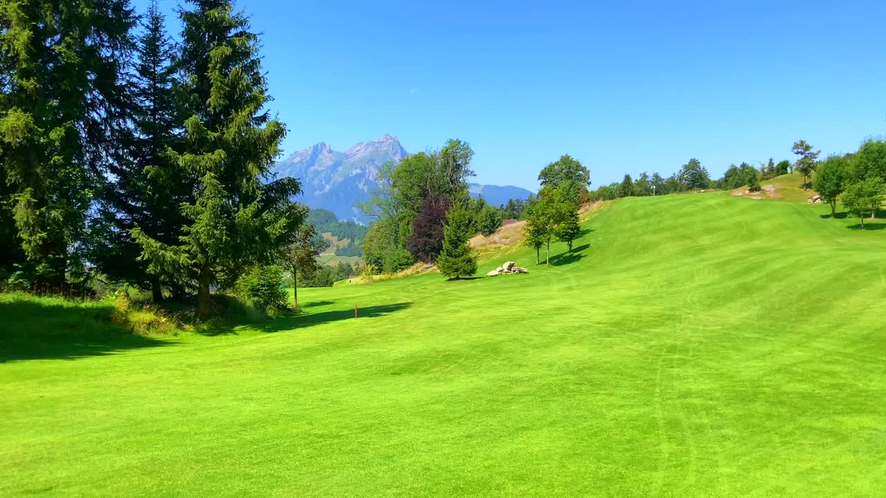 高尔夫球手走在球道与她的推车在一个阳光明媚的夏日与山景皮拉图斯视频素材