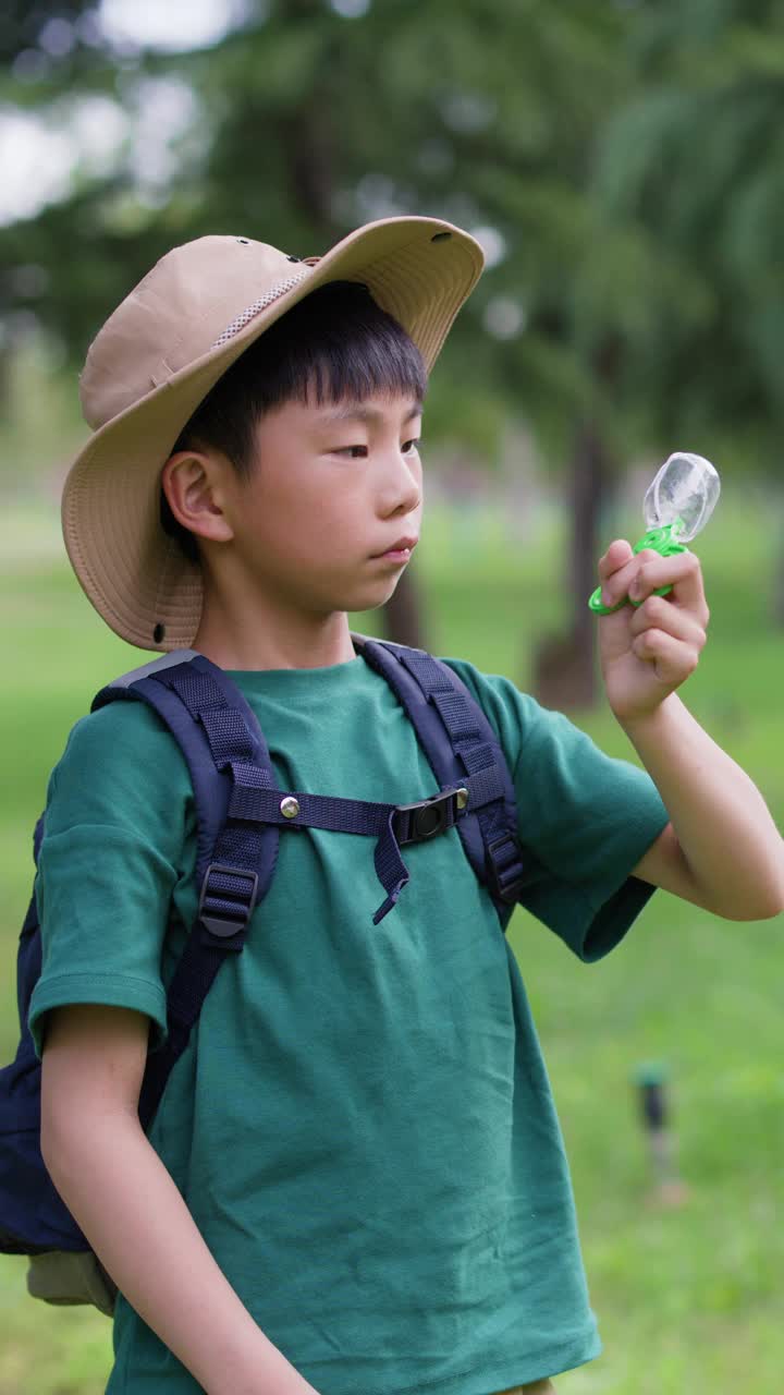 一个亚洲男孩正在观察他捉到的昆虫视频素材