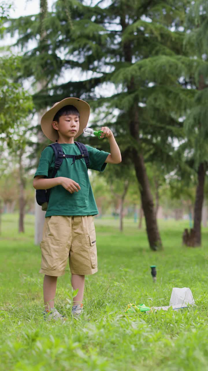 一个亚洲男孩正在观察他捉到的昆虫视频素材