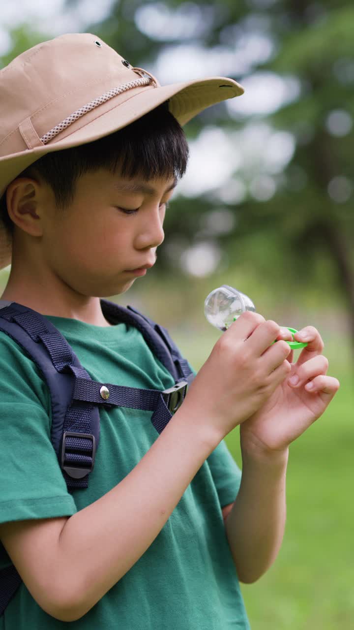 一个男孩正在观察他捉到的昆虫视频素材