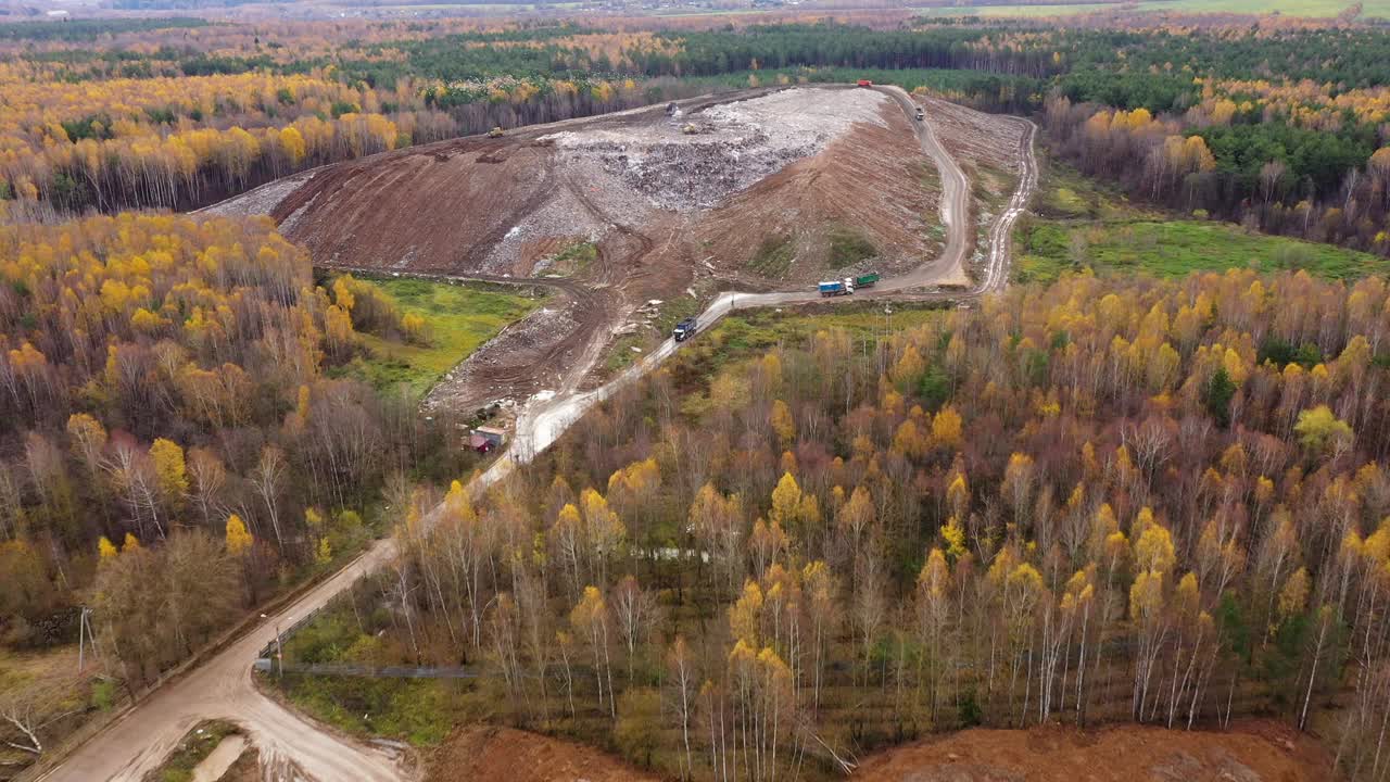 垃圾填埋场。一大堆被森林包围的垃圾。垃圾车把垃圾运到垃圾填埋场。视频素材