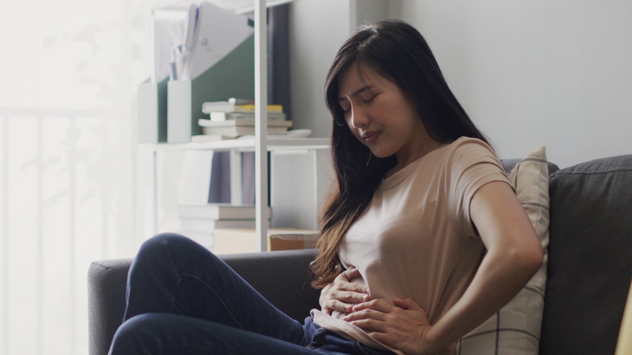 亚洲女人在沙发上胃痛视频素材