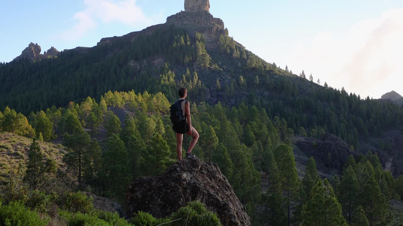 一个女人在岩石顶上徒步旅行，看风景视频下载