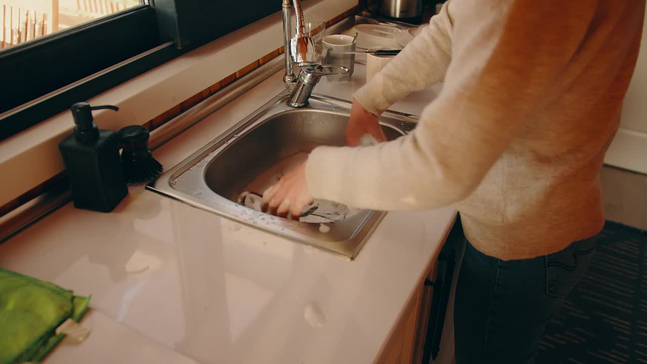 女人在家里的水槽里洗脏盘子视频素材