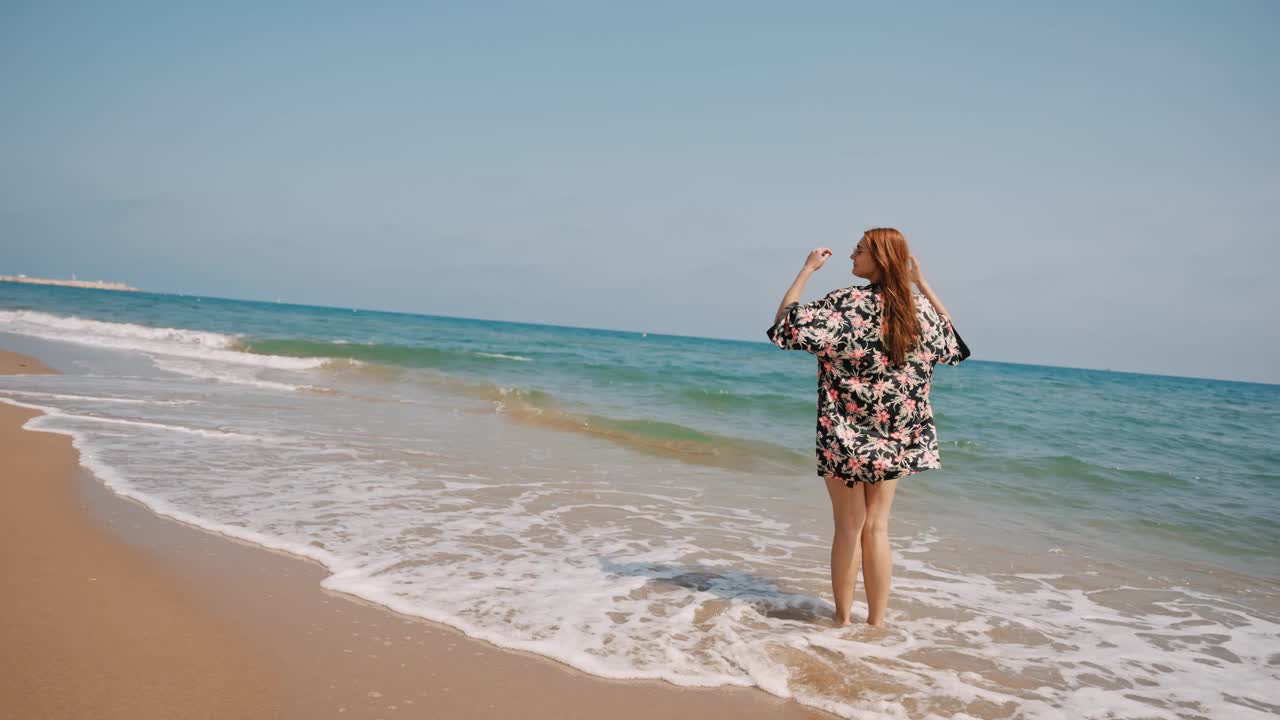 穿着背心裙的快乐女人在海滩上享受海浪视频素材