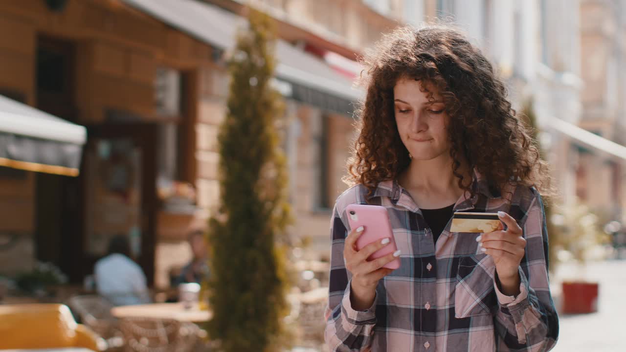 年轻女子一边用信用卡智能手机转账，一边网购视频素材