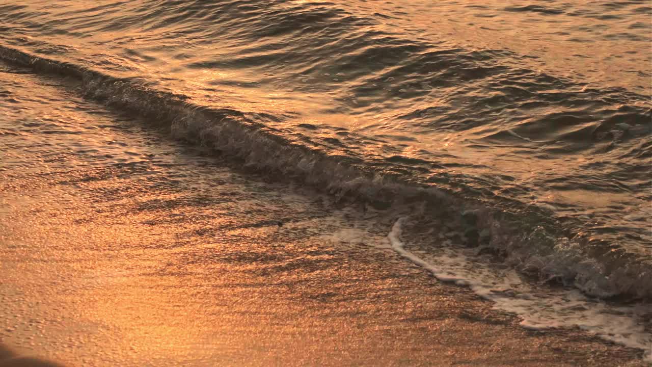 在日出或日落的热带海滩上，波浪飞溅。视频素材